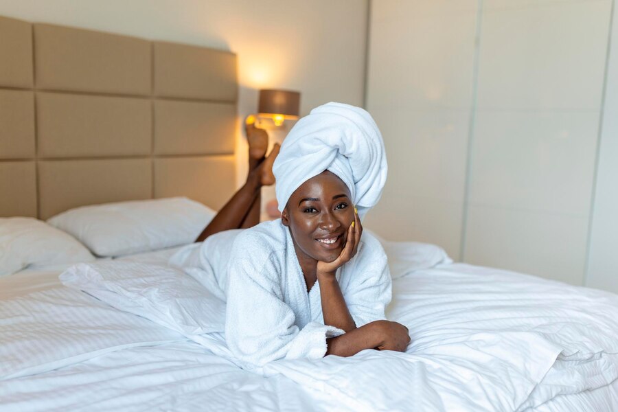 positive-start-day-smiling-african-young-woman-lying-bed-bathrobe-african-american-woman-relaxing-bed-after-bath-looking-camera_657921-1636